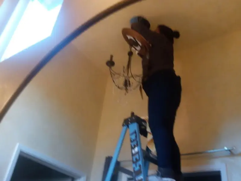 Electrician installing a chandelier in a World Golf Village residence